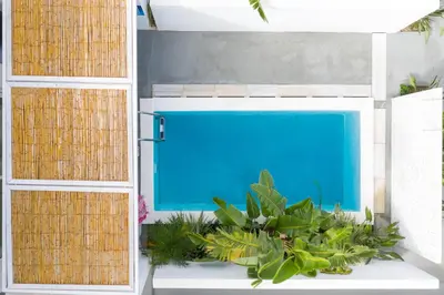 a blue swimming pool in a room with plants at Kouros Exclusive Hotel & Suites - Adults Only in Faliraki