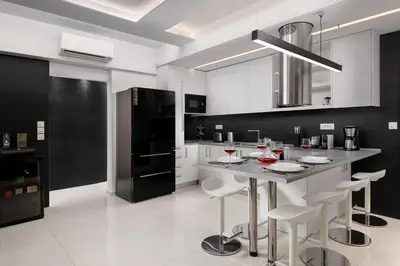 a kitchen with white cabinets and a island with bar stools at Rhodes SkyLine Suites in Ixia