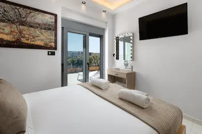 a white bedroom with a large bed and a television at Rhodes SkyLine Suites in Ixia