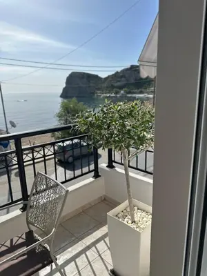 a chair and a tree on a balcony with the ocean at Orfeas Sea View House in Archangelos