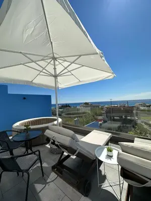 a patio with an umbrella and chairs and a table at Royal Luxury Studios in Archangelos