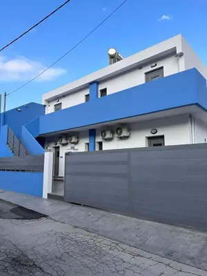 a white house with a blue fence in front of it at Royal Luxury Studios in Archangelos