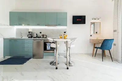 a kitchen with blue cabinets and a table and chairs at Royal Luxury Studios in Archangelos