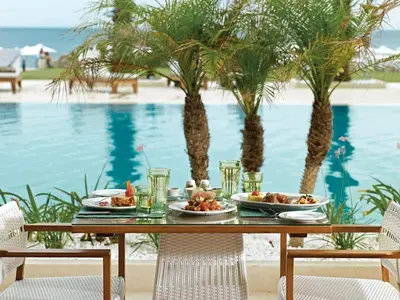 a table with plates of food next to a swimming pool at Mitsis Selection Alila in Faliraki
