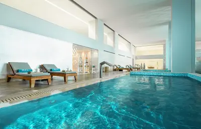 a large swimming pool with blue water in a building at Mitsis Selection Alila in Faliraki