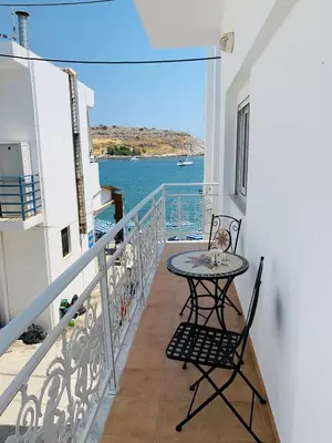a balcony with a table and chairs and a view of the water at Haraki Beach Mediterranean Retreat in Haraki