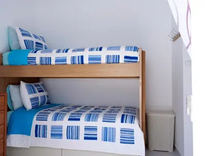 two bunk beds with blue and white sheets in a room at Haraki Beach Mediterranean Retreat in Haraki