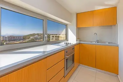 a kitchen with wooden cabinets and a large window at Sunny Penthouse,Modern Amenities+Aegean View in Rhodes Town