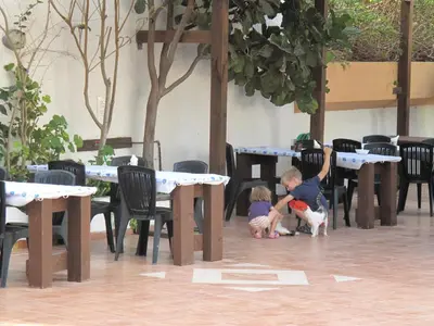 two children playing in a patio with tables and chairs at Prasonisi Club in Kattavía