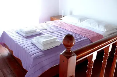 a bed with a purple comforter and towels on it at Prasonisi Club in Kattavía