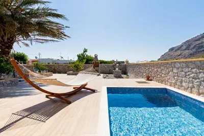 a resort with a pool and hammocks and a rock wall at Stergios summer dream house in Kolimbia