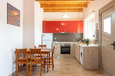 a kitchen with red cabinets and a table and chairs at Stergios summer dream house in Kolimbia