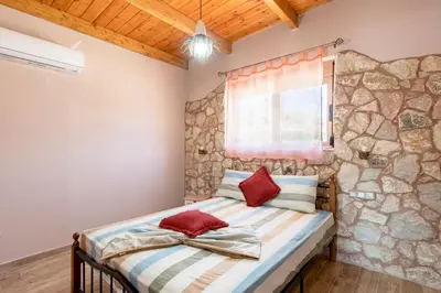 a bedroom with a bed and a stone wall at Stergios summer dream house in Kolimbia