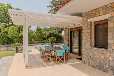 a patio with a table and chairs under a white pergola at Madia Villa in Kolimbia