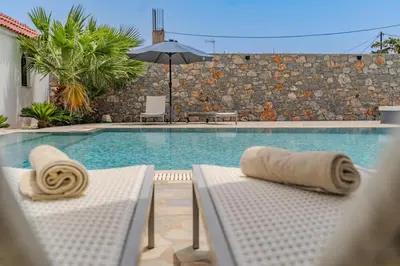 a swimming pool with two lounge chairs and an umbrella at Madia Villa in Kolimbia