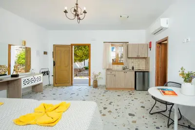 a white kitchen with a table and a yellow towel on a bed at KRANA Hotel in Líndos