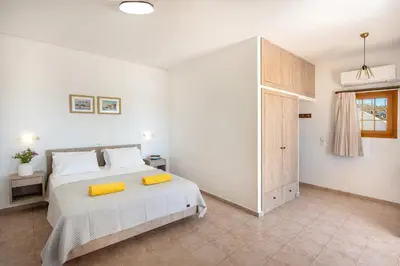 a bedroom with a large bed with yellow pillows at KRANA Hotel in Líndos