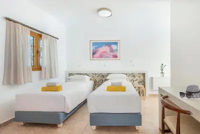two beds in a room with white walls and a desk at KRANA Hotel in Líndos