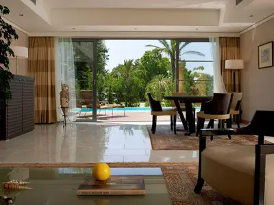 a living room with a table and chairs and a pool at ABAV2 Suites by Rodos Palace in Ixia