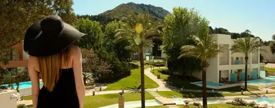 a woman in a hat is looking at a resort at ABAV2 Suites by Rodos Palace in Ixia