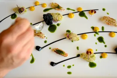 a person eating food on a white plate with flowers at ABAV2 Suites by Rodos Palace in Ixia