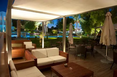 a patio with white chairs and tables and umbrellas at ABAV2 Suites by Rodos Palace in Ixia