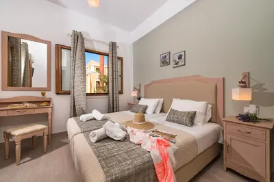 a bedroom with two beds and a table and a desk at Kokona in Symi