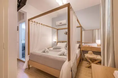 a bedroom with a bed and a desk and a mirror at Kokona in Symi