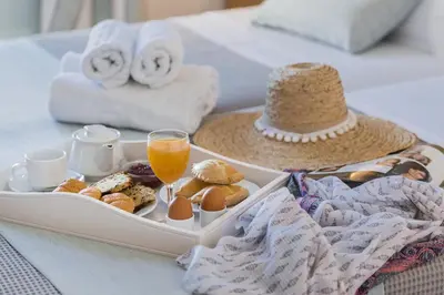 a tray of breakfast foods and a drink on a bed at Kokona in Symi