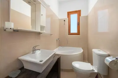 a white bathroom with a sink and a toilet at Cosy House in Kiotari with Garden and Terrace in Kiotari