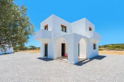 a white house on a gravel parking lot at Cosy House in Kiotari with Garden and Terrace in Kiotari
