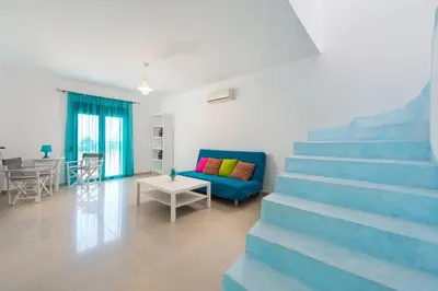 a living room with a blue couch and stairs at Cosy House in Kiotari with Garden and Terrace in Kiotari