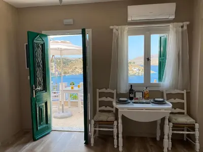 a room with a table and chairs and a window at Thodoris Infinity View Apartments in Symi