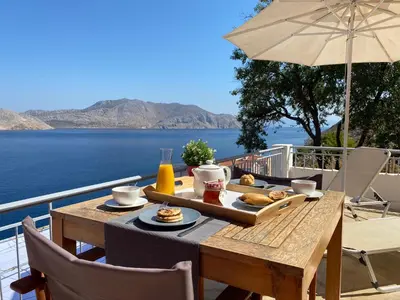 a wooden table with a tray of food on a balcony at Thodoris Infinity View Apartments in Symi