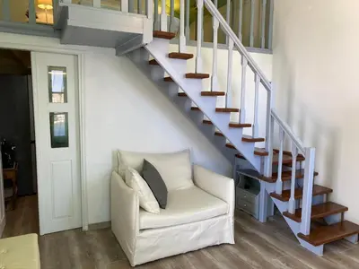 a living room with a white chair under a staircase at Thodoris Infinity View Apartments in Symi