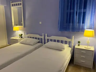 two beds in a bedroom with two lamps and a mirror at Thodoris Infinity View Apartments in Symi