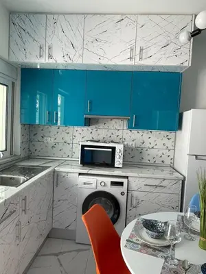 a kitchen with blue cabinets and a washing machine at The Sky Yard Eclectic Studios in Rhodes Town