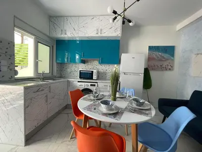 a kitchen with a white table and some chairs at The Sky Yard Eclectic Studios in Rhodes Town