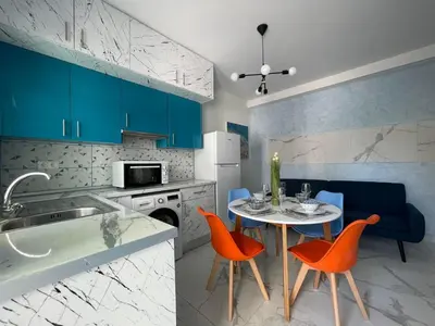a kitchen with blue cabinets and a table with orange chairs at The Sky Yard Eclectic Studios in Rhodes Town