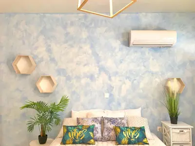 a living room with a couch and a blue wall at The Sky Yard Eclectic Studios in Rhodes Town