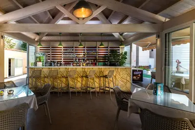 a restaurant with a bar with chairs and tables at Sunday Hotel in Ialyssos