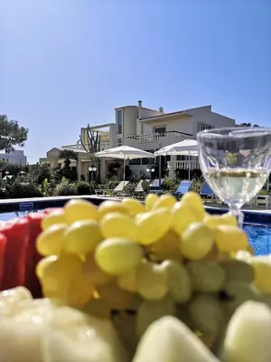 a bunch of grapes and a wine glass next to a pool at Louis Luxury Villa by living in blue in Rhodes Town