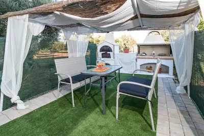 a patio with a table and chairs under a canopy at Cozy Family Home steps from the Beach in Afantou