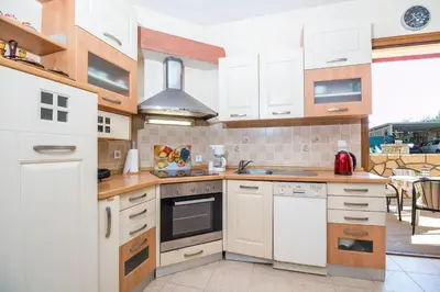 a kitchen with white cabinets and a stove top oven at Cozy Family Home steps from the Beach in Afantou
