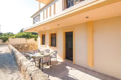 a patio with a table and chairs next to a building at Cozy Family Home steps from the Beach in Afantou