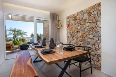 a dining room with a table and a stone wall at Venezia Luxury Living Villas, Faliraki in Faliraki