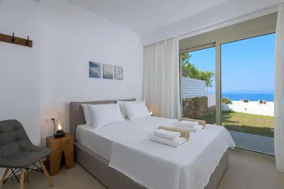 a bedroom with a bed and a chair and a window at Villa Allegra with pool in Pefkos, Lindos area in Pefki Rhodes