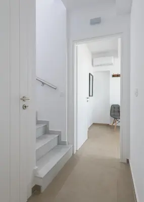 a white hallway with stairs and a door at Villa Allegra with pool in Pefkos, Lindos area in Pefki Rhodes