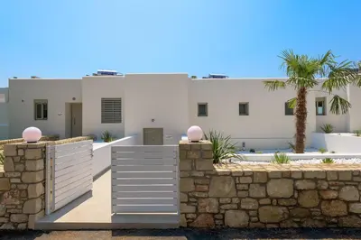 a white house with a stone wall and palm trees at Villa Allegra with pool in Pefkos, Lindos area in Pefki Rhodes