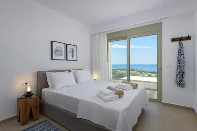 a white bedroom with a large bed with towels on it at Villa Mimosa in Pefkos (Lindos area) in Líndos